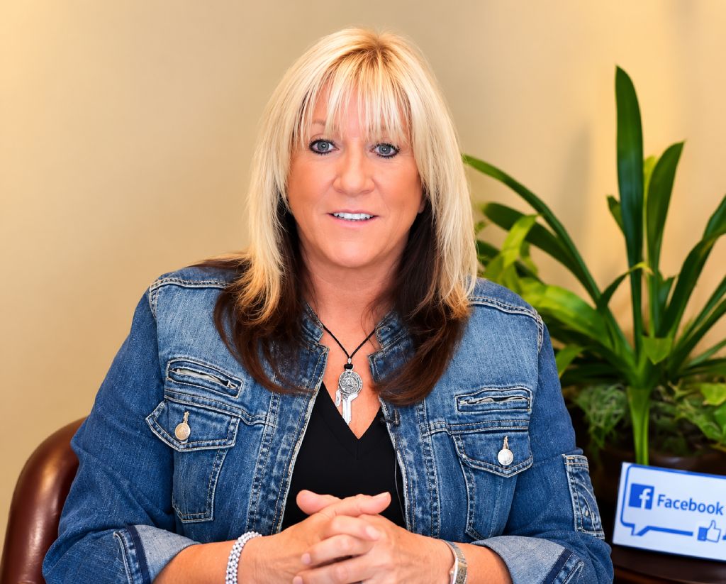 Smiling woman in a denim jacket sharing a video testimonial