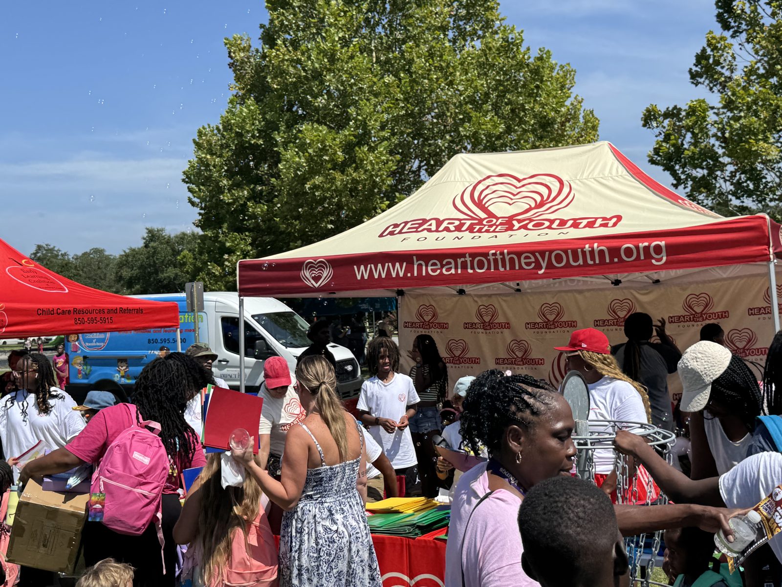 Volunteers handing out school supplies under a tent at the Pensacola back-to-school outreach event